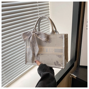 Detail of grey canvas tote bag with butterfly embroidery and silk scarf handle decor