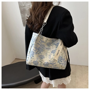 Close-up of floral tote bag with chain strap and embroidered fashion label detail