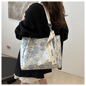 Floral canvas tote bag with embroidery details and ribbon shown on model shoulder