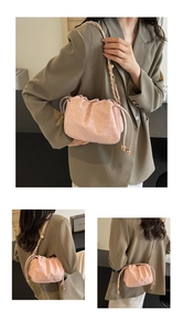 Dettaglio borsa a nuvola rosa con coulisse, catena dorata e decori a sfera metallica