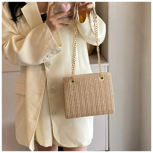 Detail of woven straw shoulder bag with herringbone texture and gold chain straps