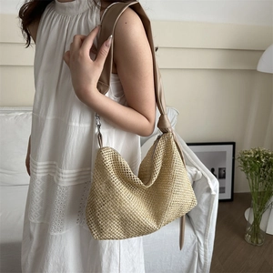 Woven straw tote bag with khaki leather shoulder strap and knot detail in cozy interior