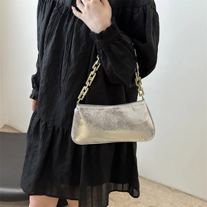 Silver metallic shoulder bag with chunky gold chain strap worn by a model