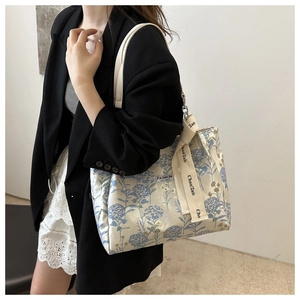 Detail of off-white tote bag with blue hydrangea embroidery and fashion ribbon strap
