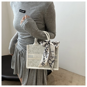 Close-up of floral tote bag with branded silk scarf and elegant jacquard texture