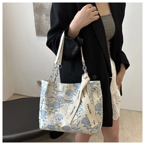 Detail of canvas tote bag with blue hydrangea floral print and fashion chain strap