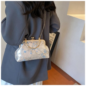 Detail of vintage silver handbag with blue floral embroidery and golden round handle