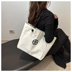 Detail of white large canvas tote bag with black logo and drawstring shoulder strap