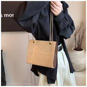 Detail of bohemian straw bag with brown leather trim and golden metal chain strap