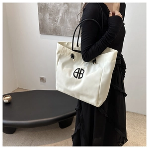 Detail of white nylon tote bag with black logo and adjustable knot straps for women