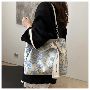 Close-up of floral tote bag featuring dual shoulder straps and fashion logo patch