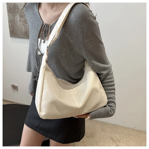 Close-up of minimalist off-white PU leather hobo bag with wide adjustable shoulder strap