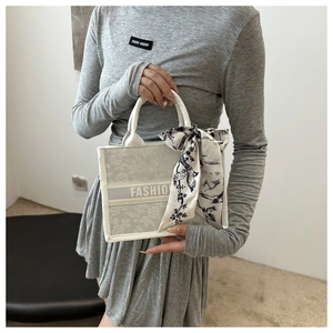 Detail of floral embroidery on a light green canvas tote with a decorative silk scarf