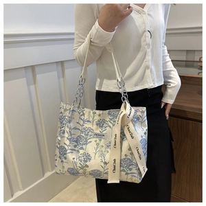 Detail of floral tote bag with silver chain handles and fashion decorative ribbon