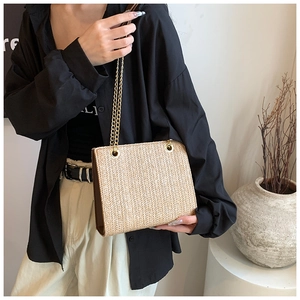 Detail of beige woven tote bag with V-shaped texture and gold metal chain straps