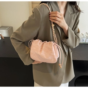Detail of pink pleated cloud bag featuring drawstring closure and gold chain strap