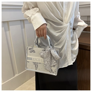 Close-up of silver tote bag with butterfly print and fashion logo detail