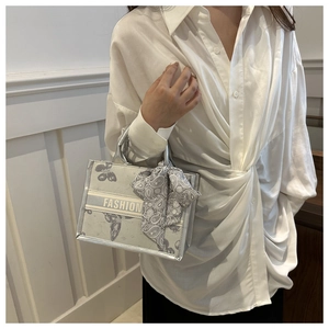 Detail of silver-grey tote bag with butterfly pattern and silk scarf on handle