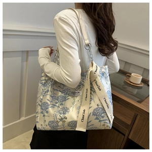 Detail of floral canvas tote bag featuring metal chain strap and blue flower pattern