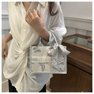 Detail of silver-grey tote bag with butterfly prints and silk scarf on the handle