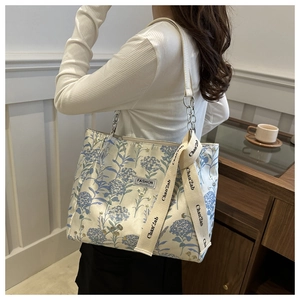 Detail of floral canvas tote bag with leather straps and metal fashion instinct plaque