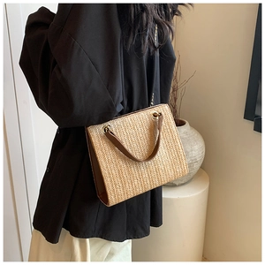 Detail of woven straw tote bag with V-pattern texture and brown leather handle