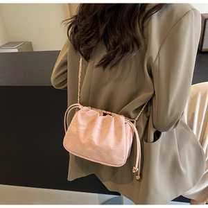 Close-up of pink pleated crossbody bag featuring drawstring closure and gold chain strap