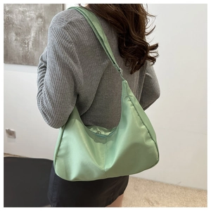 Detail view of a light green hobo bag featuring wide shoulder strap and soft nylon texture