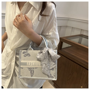 Detail of silver canvas tote bag featuring butterfly print and paisley silk scarf handle