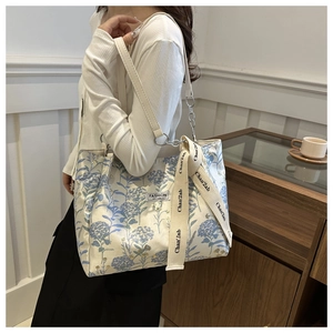 Detail of floral tote bag with white leather straps and fashion instinct logo tag