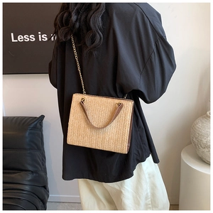 Detail of woven straw shoulder bag with leather handles and gold chain strap