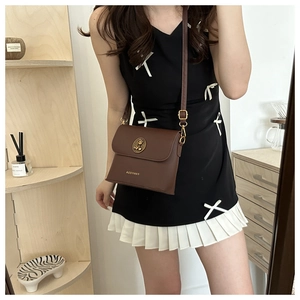 Detailed view of brown matte leather shoulder bag with gold logo and adjustable strap