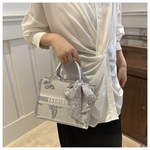 Silver metallic tote bag with butterfly pattern and silk scarf handle detail