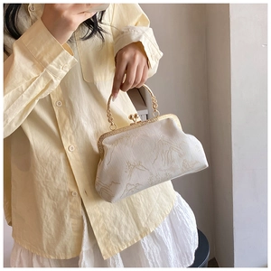 Close-up of elegant mountain landscape embroidery on retro ivory cheongsam bag with metal handle