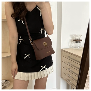 Brown leather crossbody bag detail featuring golden bear emblem and Fanyissa logo