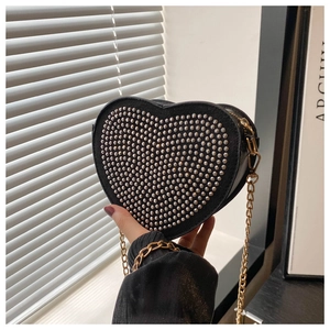 Detailed view of heart-shaped black crossbody bag featuring silver metal rivets and gold chain