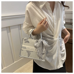 Detail of silver grey tote bag with butterfly patterns and silk scarf on a handle