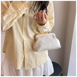 Detailed close-up of cream jacquard handbag with landscape pattern and gold metal clasp