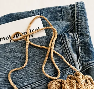 Gros plan détaillé de la bandoulière en corde tressée beige d'un sac à main en paille