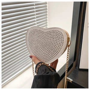 Detail of white heart-shaped tote bag with silver studs and golden chain strap
