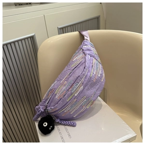 Detail of purple chest bag featuring colorful embroidery stripes and a plush soot sprite charm