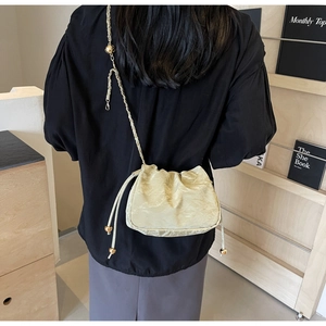 Dettaglio della borsa nuvola a pieghe champagne con texture morbida e catena oro