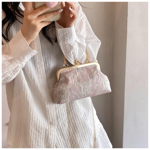 Close-up of vintage jacquard clasp bag with gold floral patterns and delicate chain strap