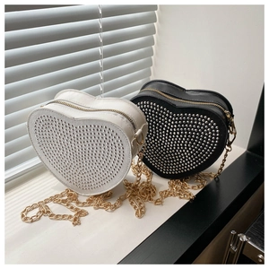 Detail of heart-shaped crossbody bags in black and white with silver studded metal rivets