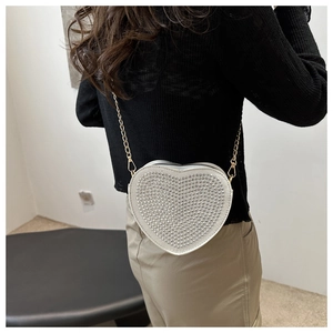 Side view of heart-shaped crossbody bag with silver studs and gold metal chain strap