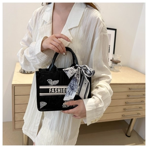 Detail of canvas tote bag with fashion lettering, butterfly embroidery and silk scarf