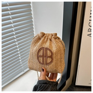 Texture détaillée d'un mini sac seau en paille tissé avec écusson logo AB marron