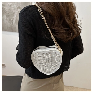 Detail of white heart shaped crossbody bag with silver studs and golden chain strap