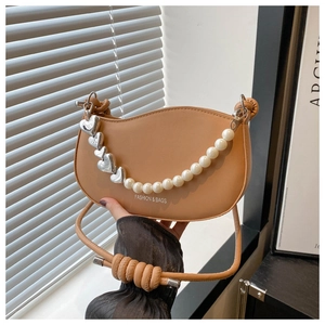 Detailed view of brown faux leather crescent bag with pearl heart chain and knot strap