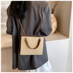 Chic beige houndstooth woven tote bag with brown handles and gold chain strap on model
